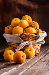 Apricots group in basket on old rustic wooden table and dark background