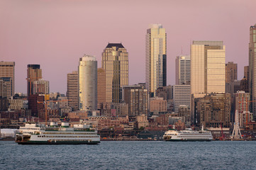 Obraz premium Seattle Skyline at Sunset. During a beautiful Seattle, Washington sunset ferry boats run between Bainbridge Island and downtown Seattle. Modern skyscrapers line the waterfront.