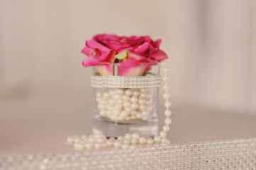 Бутон красной розы в вазе с жемчугом