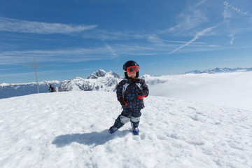 Fototapeta na wymiar Cute little skier and alpine panorama.