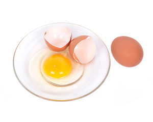 Cracked brown eggs on plate separated on white background