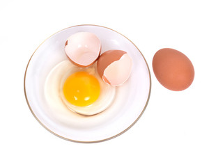 Cracked brown eggs on plate separated on white background