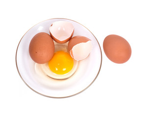 Cracked brown eggs on plate separated on white background