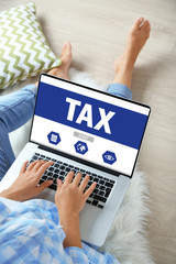 Online Tax payment concept. Woman working with laptop at home