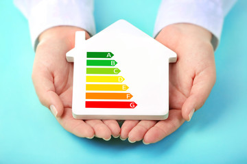 Female hands holding house with energy efficiency scale image