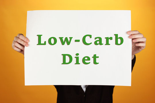 Woman holding paper with Low-Carb Diet text on color background