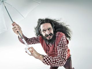 Funny portrait of a nerdy guy holding an umbrella