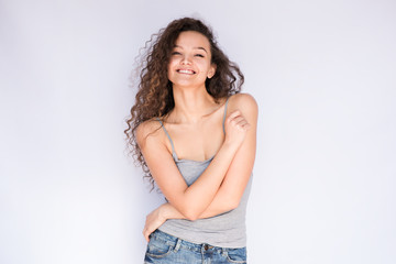 Smiling young woman with curls hugging her body