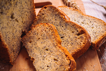 Close slice of fresh bread with poppy seeds on a wooden background