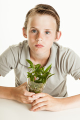 Boy holding glass with weeds on white background