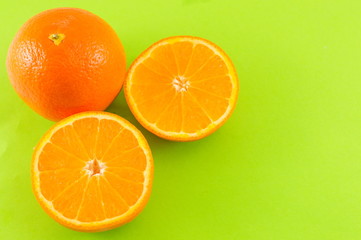 Whole and sliced orange on green background