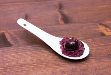 Olive paste on spoon on wooden table