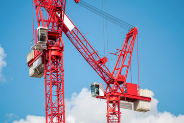 Two Red Construction Tower Cranes Against Blue Sky. Construction Industry Concept