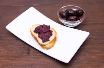 Slice of bread with olive paste on wooden table