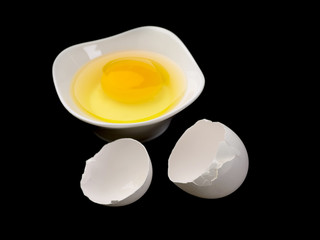 egg yolk in white plate with egg shell