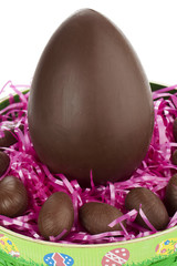 easter egg surrounded by chocolates on the top of shredded paper