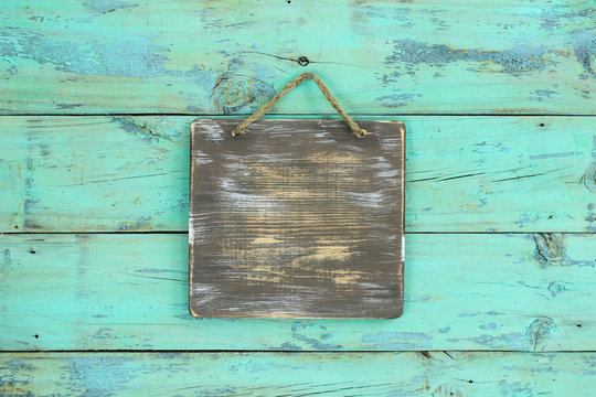 Blank rustic sign hanging on antique mint green wood background