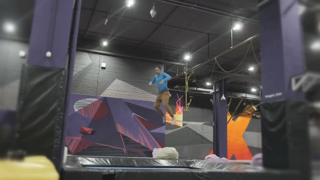 Professional Gymnast doing Tricks on Trampoline. Flips in Air. High Extreme Jumps by Professional Athlete.