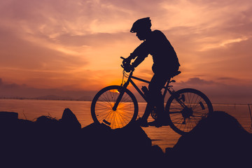 Healthy lifestyle. Silhouette of bicyclist riding the bike at seaside.