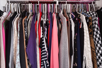 Crowded closet of colorful women's clothing on hangers