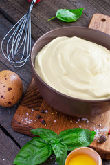 Homemade mayonnaise sauce in a bowl on a wooden background