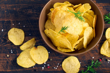 Crispy potato chips with a bowl, top view