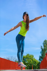 Teen girl skater riding skateboard on street.