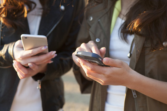 Two young women are each other to show the smartphone