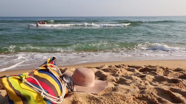 Women's beach accessories on the beach by the sea. Hat picked up by the wind