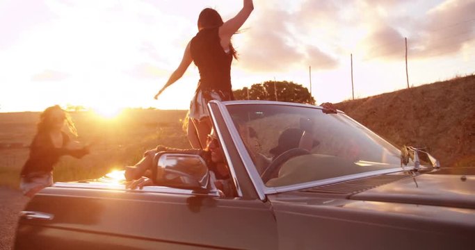 Teenage boho friends embraging and laughing at sunset