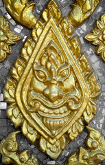 Fototapeta na wymiar Golden giant face sculpter at Thai temple wall