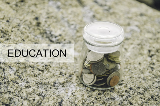 Financial image concept with word EDUCATION. Blurred background coin in glass jar on the rock.