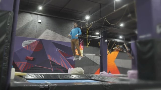 Professional Gymnast doing Tricks on Trampoline. Flips in Air. High Extreme Jumps by Professional Athlete.