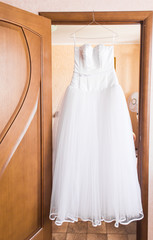 The perfect wedding dress on a hanger in the room of bride 