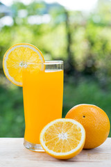 Orange juice and slices of orange isolated on wooden table, on g