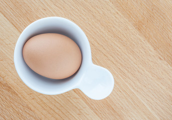 Top view of boiled egg served in egg cup on wooden table.