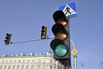 Traffic light against the blue sky and the pedestrian sign