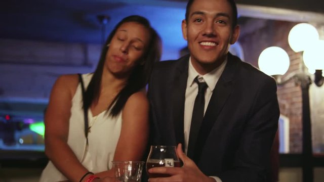 Well dressed man and woman posing for an awkward picture together at a nightclub