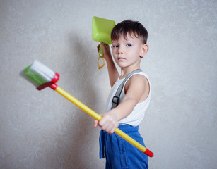 Serious little boy holding brooms in tough pose