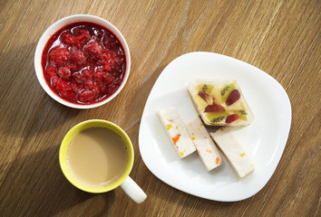 Coffee with milk, cake and strawberry jam