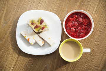 Coffee with milk, cake and strawberry jam