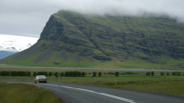 Icelandic landscape. Panorama of the mountains in Iceland. Icelandic moss in the foreground and snow-capped mountains in the background. On the road going car