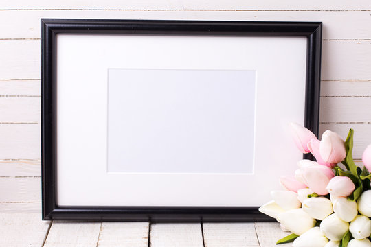 Empty frame and  pink flowers  on white wooden background.