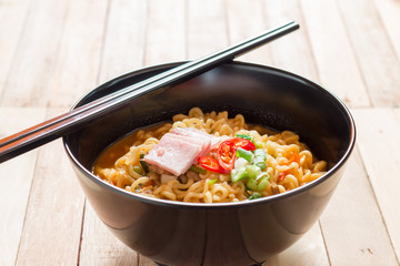 Korean noodles(Ramyun) in black bowl on wooden table.