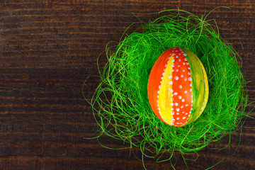 Easter egg in beautiful and different colors lie on the grass on wooden background
