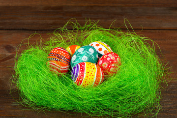 Easter egg in beautiful and different colors lie on the grass on wooden background
