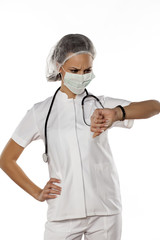 a young woman doctor with cap and mask looking at her wristwatch