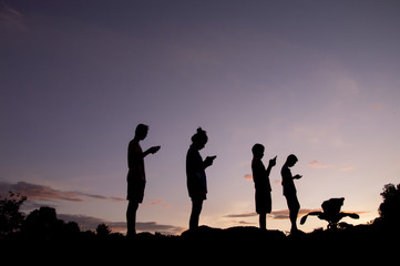 Fototapeta na wymiar Phubbing, Silhouette of children taking smart phone at sunset sky