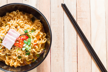 Top view of korean noodles(Ramyun) in black bowl on wooden table.