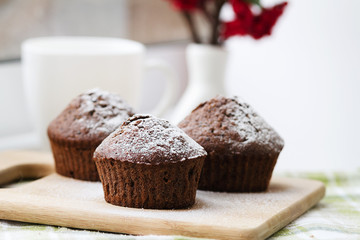 Chocolate cupcakes with icing sugar on a wooden table